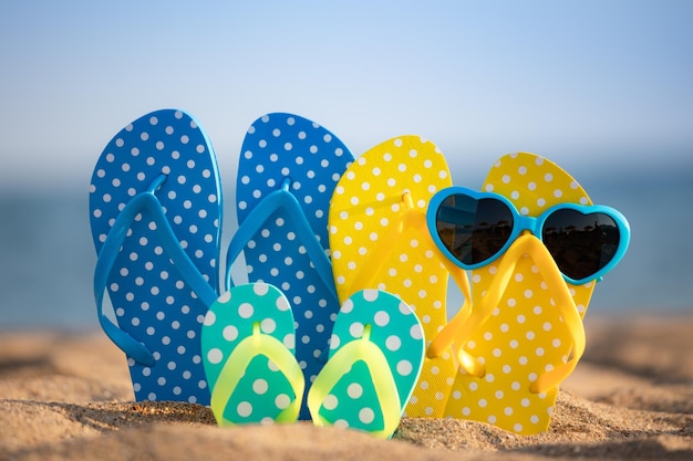 Tongs de plage sur le sable sur fond de mer et de ciel Concept de vacances d'été