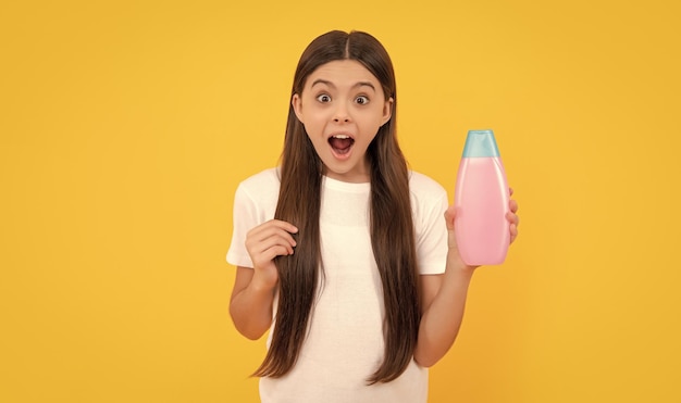 Étonné adolescente cheveux longs avec lotion pour le corps sur la beauté de fond jaune