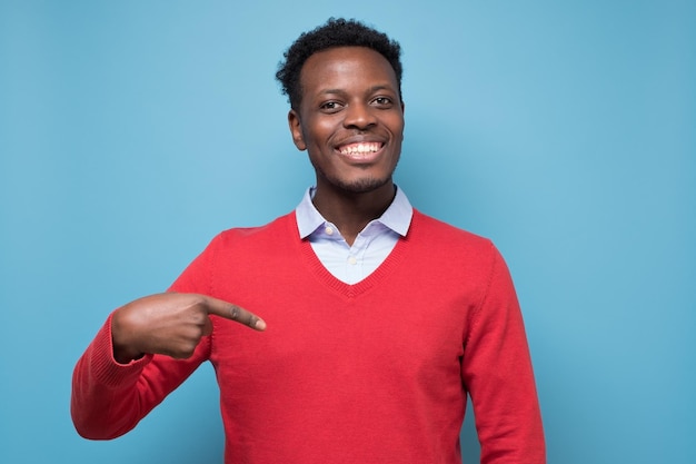Étonné étudiant homme africain pointant le doigt de côté à l'espace de copie