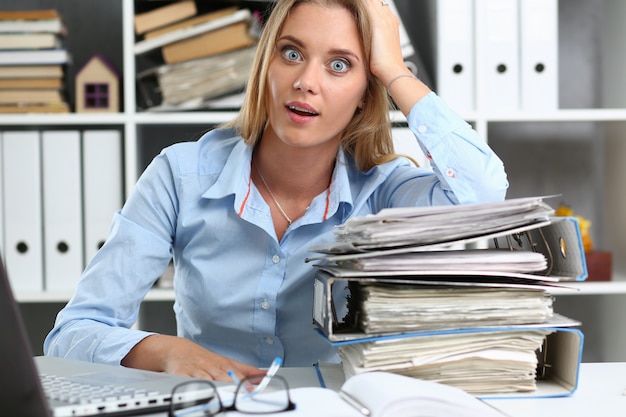 Étonné de jeune femme ayant beaucoup de travail au bureau