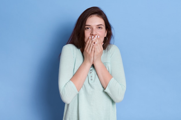 Étonné jeune femme couvrant la bouche avec les mains