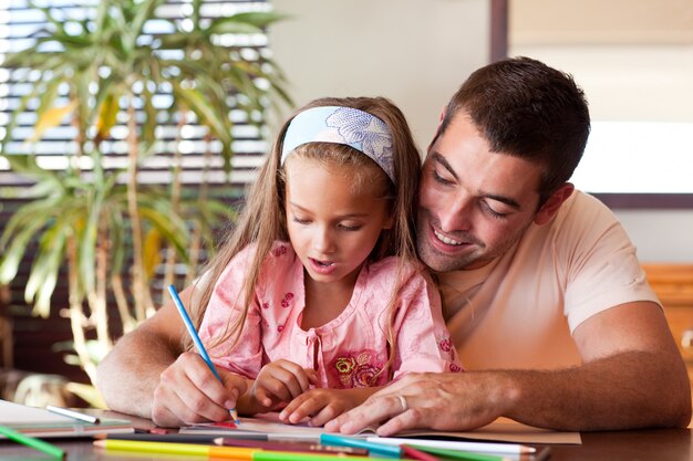 Étonné petite fille dessin avec son père souriant