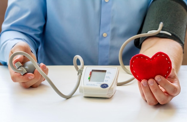 Tonomètre numérique et figurine de coeur dans les mains