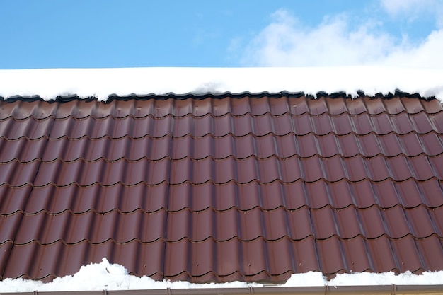 Photo top du toit de la maison à partir de carreaux métalliques bruns avec de la neige dans une journée d'hiver ensoleillée