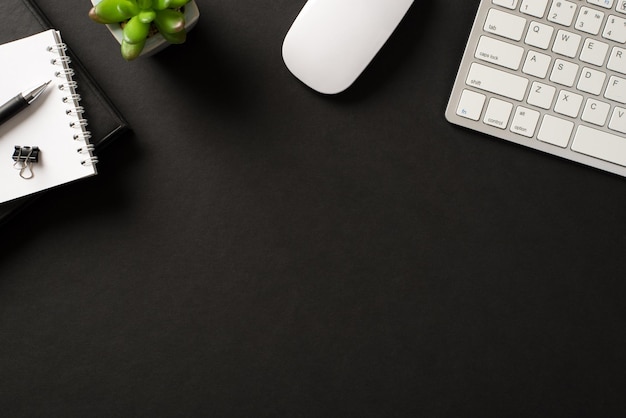 Top flatlay au-dessus de la vue aérienne photo de clavier de trucs de bureau carnet de planificateur succulent vert avec stylo fond noir isolé avec place pour le texte de conception