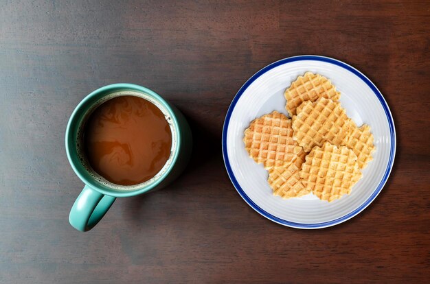 Photo top view café mocha dans une tasse verte et de nombreuses gaufres sur un plat sur une table en bois