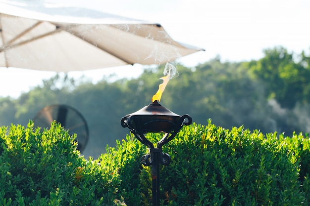 Torche allumée avec flamme orange dans le jardin utilisé comme anti-moustique