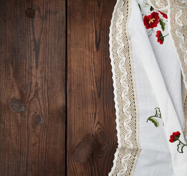 Torchon blanc brodé de dentelle sur une table en bois marron