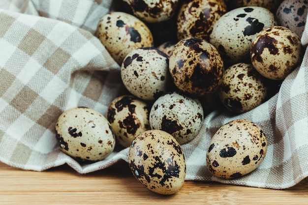 Torchon plein d'oeufs de caille sur une table en bois