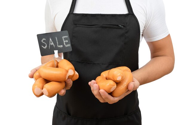 Torse d'un homme dans un tablier noir avec des saucisses et une étiquette de prix dans ses mains isolé sur blanc