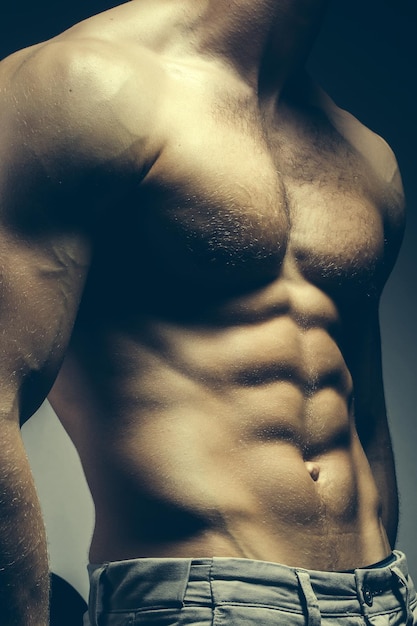 Torse masculin musclé sexy de bodybuilder athlète posant au pouvoir avec des veines sur les mains et la poitrine nue sur fond gris