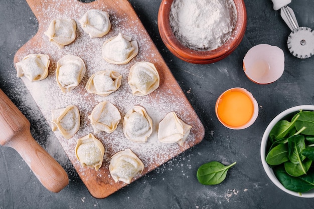 Tortellini maison cru frais ou pâtes ravioli aux épinards sur fond sombre