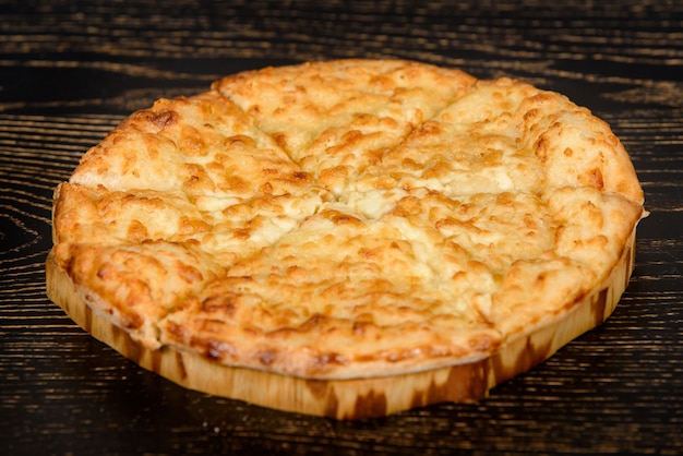 Tortilla cuit avec du fromage sur une plaque en bois sur une table en bois sombre. Pâtisseries au fromage avec une croûte croustillante.