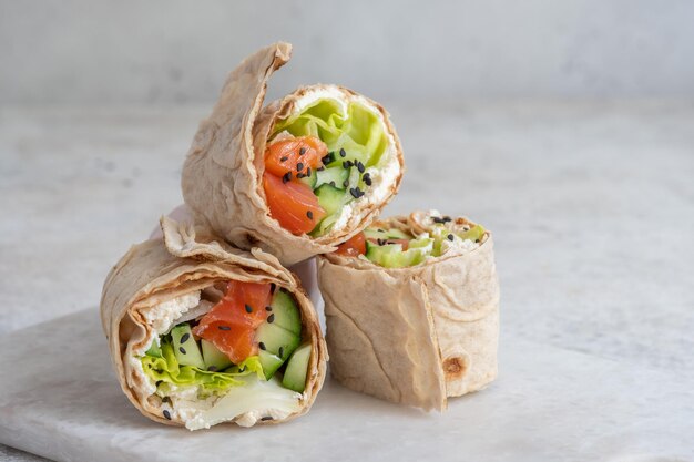 Tortilla avec fromage crémeux de saumon et légumes sur assiette blanche