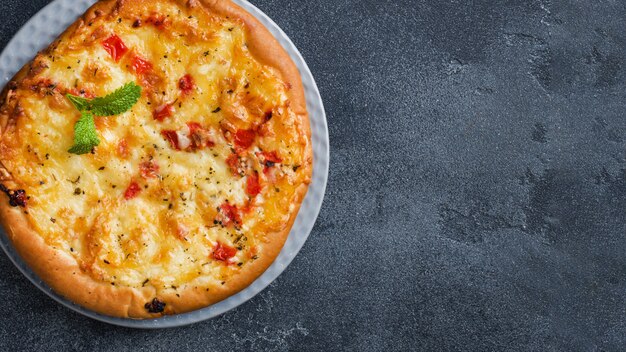 Tortilla pizza maison avec tomate et fromage sur fond de béton gris.