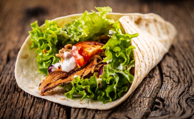 Tortilla avec viande, tomate, salade, oignon et crème.