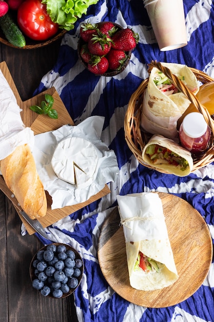 Tortillas au poulet et légumes rôtis, jus de fruits frais, divers légumes et baies, baguette et fromage