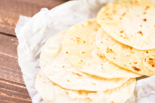 Tortillas de maïs blanc frais sur un papier blanc.