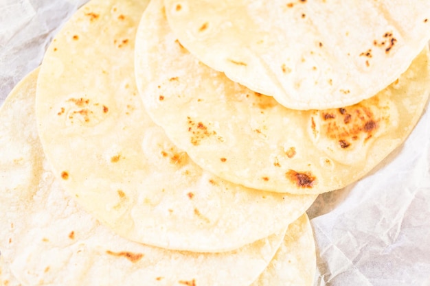 Tortillas de maïs blanc frais sur un papier blanc.