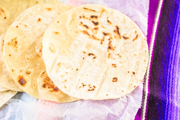 Tortillas de maïs blanc frais sur un papier blanc.