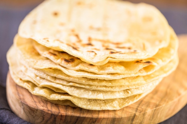 Tortillas de maïs blanc frais sur une planche à découper.