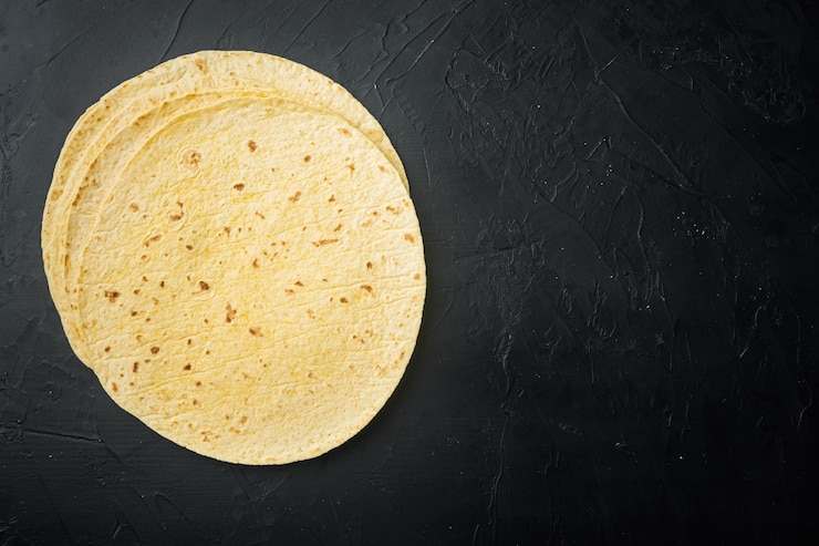 Photo tortillas de maïs mexicain, sur fond noir, vue de dessus à plat avec copie espace pour le texte