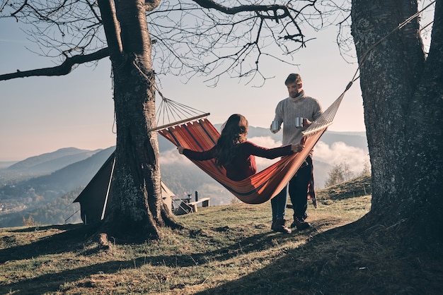 Totalement détendu. Belle jeune femme gardant les bras tendus tout en se relaxant dans un hamac à l'extérieur