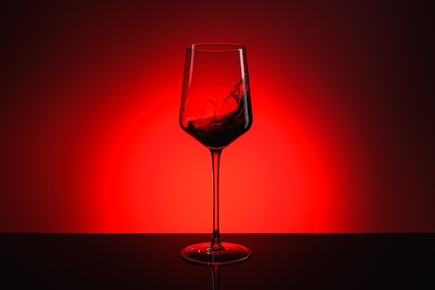 Une touche de vin dans un verre sur fond rouge.