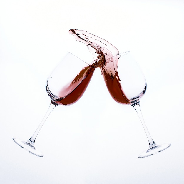 Une touche de vin rouge de deux verres en verre isolé sur une surface blanche