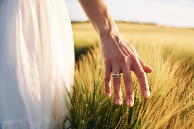 Toucher le blé Belle jeune mariée en robe blanche est sur le terrain agricole aux beaux jours