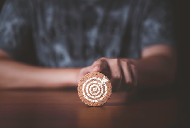 Toucher à la main et pousser le tableau cible qui imprime sur un bloc rond en bois pour créer et mettre en place un concept d'objectif cible d'objectif commercial