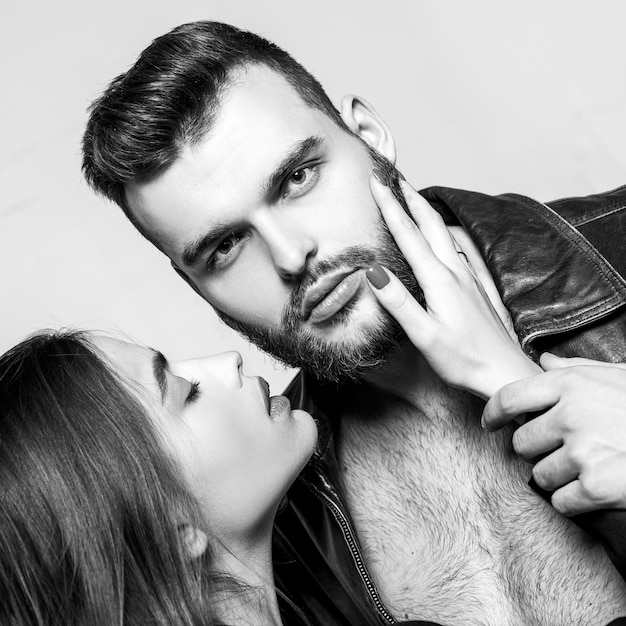 Toucher ses poils Elle adore la barbe masculine Câlin passionné Couple passionné amoureux Homme brutal bien soigné macho et jolie fille câlins Petite amie passionnée lèvres rouges et veste en cuir homme