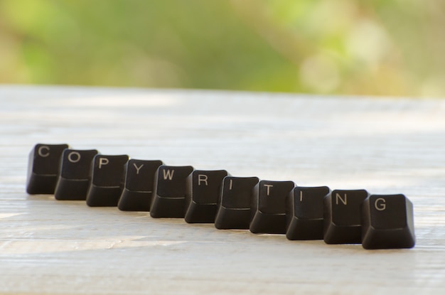 Sur les touches noires du clavier est écrit le mot Rédaction sur une table blanche en plein air