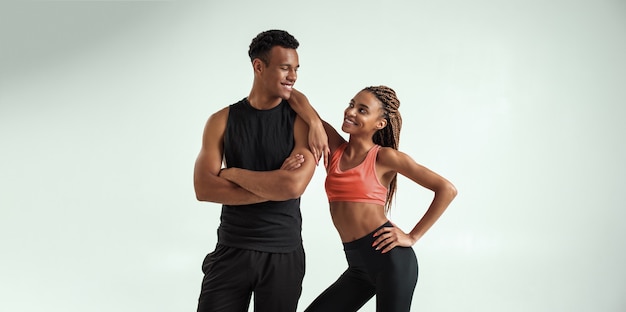 Toujours ensemble jeune couple de fitness africain en tenue de sport se regardant et souriant tout en