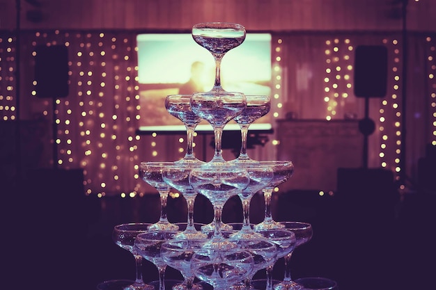 Photo tour de champagne construite en arrière-plan d'un couple d'amoureux photo projetée tour de verres dans la salle de banquet éclairée sombre tour de mariage de champagne au centre de la fabuleuse salle de mariage