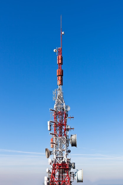 Une tour de communication radio avec des plats contre un ciel bleu profond