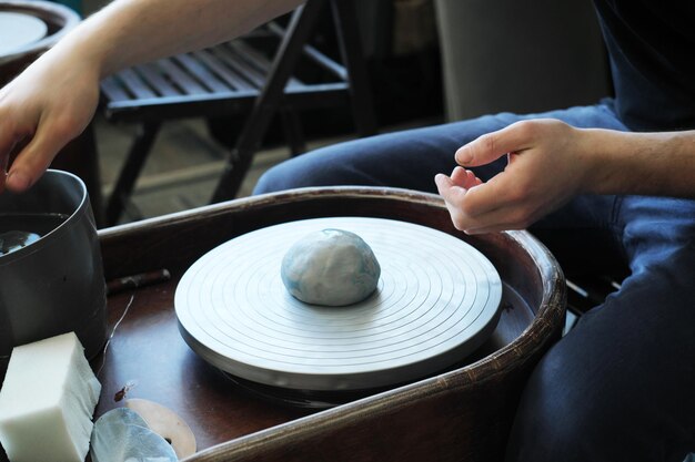 Sur le tour du potier se trouve un morceau d'argile en forme de boule Un potier travaille dans un atelier de poterie