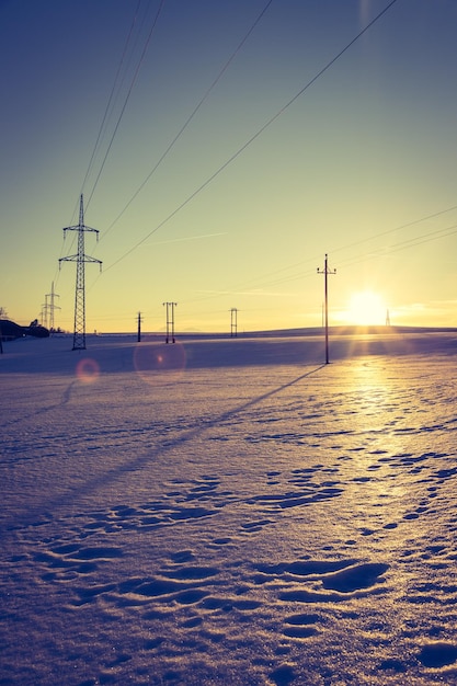 Tour électrique sur un champ enneigé Le soleil se couche couleurs orange paysage du soir