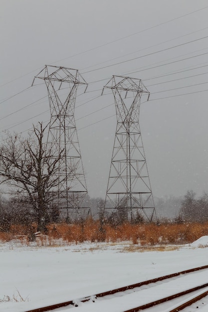 Tour électrique des lignes électriques en hiver avec des champs couverts de neige