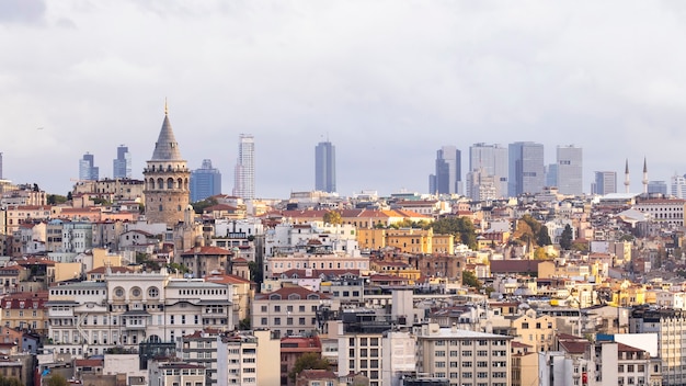 Tour de Galata avec des niveaux de bâtiments résidentiels en face d'elle et des bâtiments modernes par temps nuageux Istanbul, Turquie