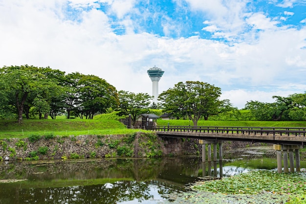 La tour Goryokaku en été, un jour ensoleillé, des nuages blancs et un ciel bleu. La tour est sur le pont de l'observatoire.