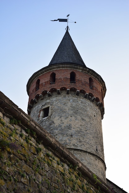 Tour de guet ronde élevée d'une forteresse ou d'un château médiéval et d'une partie d'un mur de pierre contre un ciel bleu