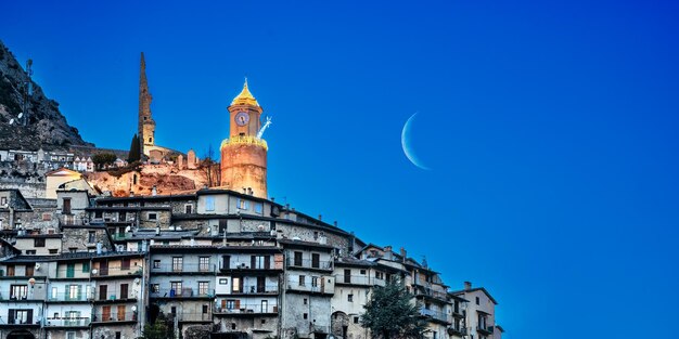 Tour de l'horloge et ruines du château haut sur la colline de maisons empilées dans le village médiéval de Tende dans les AlpesM