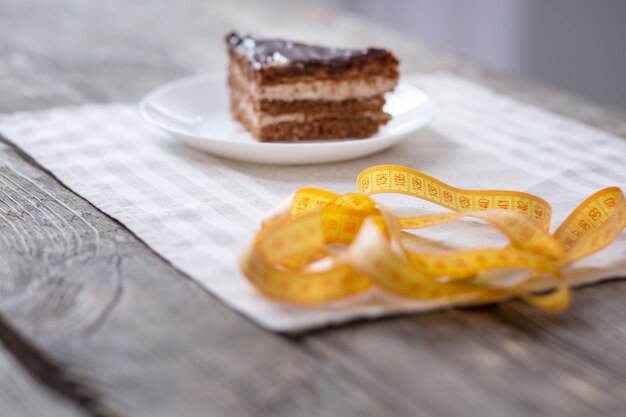 Photo tour de taille. ruban centimètre jaune posé sur la table près du morceau d'un délicieux gâteau