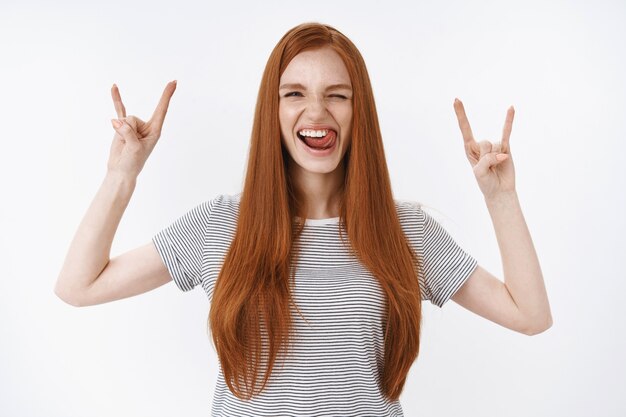 Tour de taille vif cool rousse joyeuse amusée adolescente bâton langue appareil photo clin d'œil ludique amusez-vous profiter de superbe concert du festival spectacle rock-n-roll soulèvement du métal geste, mur blanc