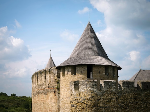 Tour à toit conique et merlons d'un château médiéval contre un ciel bleu