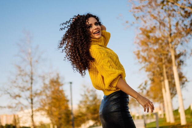 Tourbillonne joyeusement et se frotte les mains les cheveux d'une fille dans le parc à l'automne