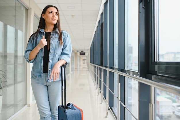 Tourisme vacances vacances enfance et concept de transport souriante petite fille avec sac de voyage sur fond d'aéroport