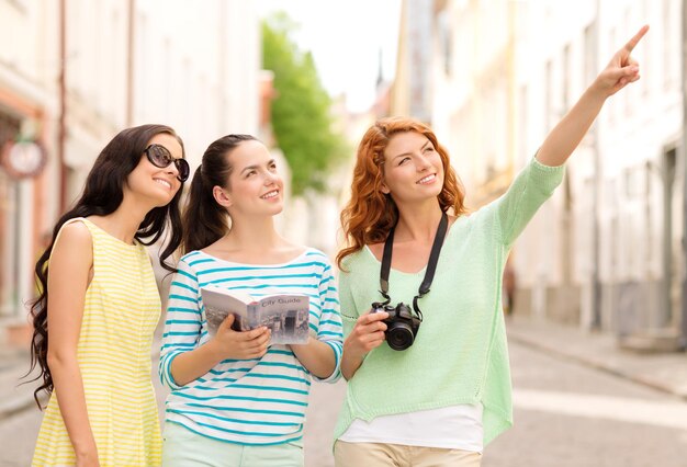 tourisme, voyage, loisirs, vacances et concept d'amitié - adolescentes souriantes avec guide de la ville et appareil photo à l'extérieur