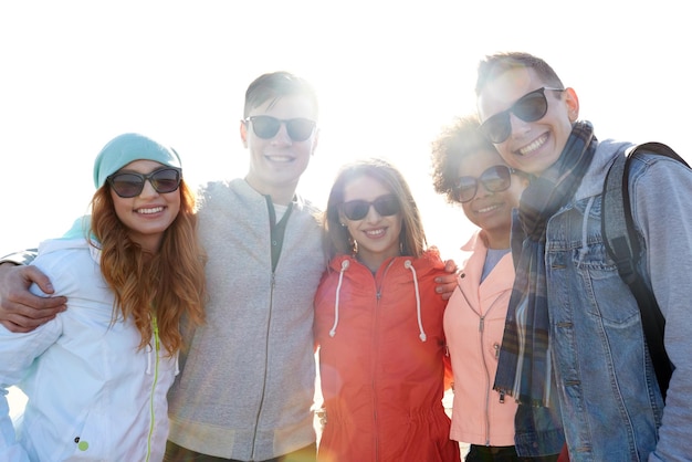 tourisme, voyages, personnes, loisirs et concept adolescent - groupe d'amis heureux en lunettes de soleil étreignant dans la rue de la ville